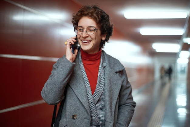 Mulher de negócios com um smartphone em uma passagem subterrânea vazia do metrô