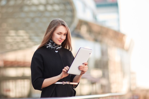 Mulher de negócios com um tablet digital, perto do centro de negócios. pessoas e tecnologia
