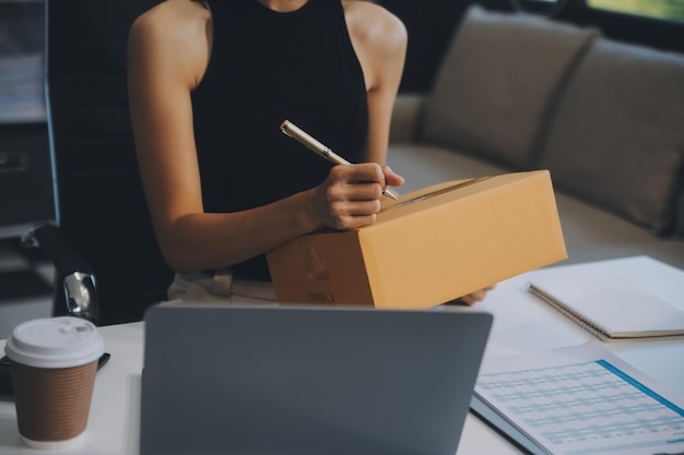 Foto mulher de negócios começa uma pequena empresa e empresárias bem-sucedidas de pme mulher asiática hoding boxs trabalha em casa entregando encomendas on-line conceito de entrega e embalagem de pme