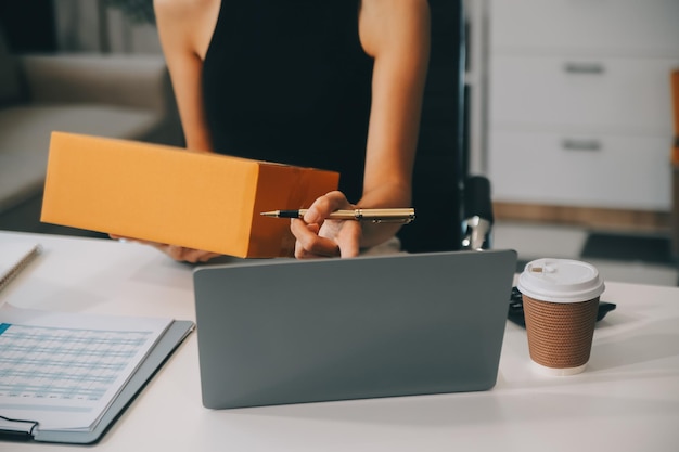 Foto mulher de negócios começa uma pequena empresa e empresárias bem-sucedidas de pme mulher asiática hoding boxs trabalha em casa entregando encomendas on-line conceito de entrega e embalagem de pme