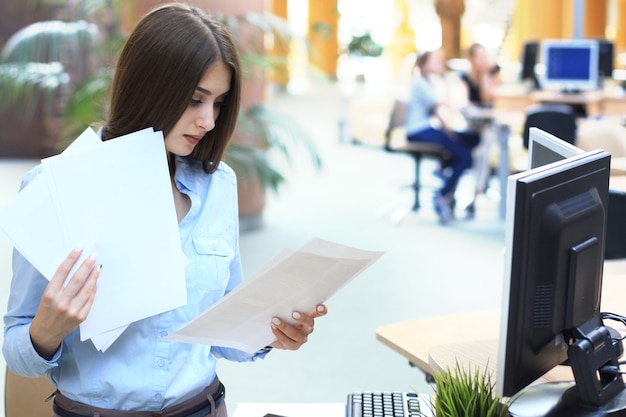 Mulher de negócios concentrada comparando documentos no escritório.