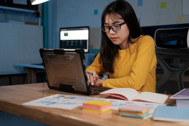 Mulher de negócios concentrada trabalhando até tarde com seu laptop.