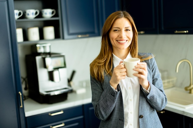 Mulher de negócios confiante desfrutando de uma pausa para café em uma cozinha de escritório moderna