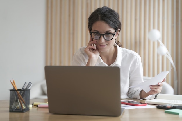 Mulher de negócios confiante sorridente trabalha no computador em casa, consultando clientes remotamente on-line