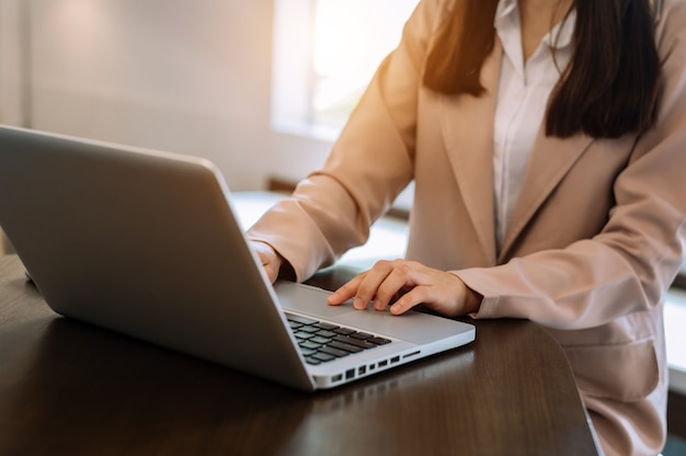 Mulher de negócios confiante trabalhando no laptop e tablet em seu local de trabalho no escritório moderno.