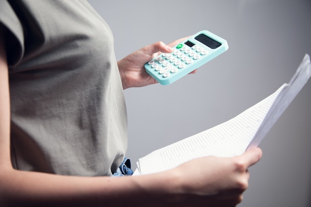 Foto mulher de negócios contando com calculadora e segurando documentos nas mãos