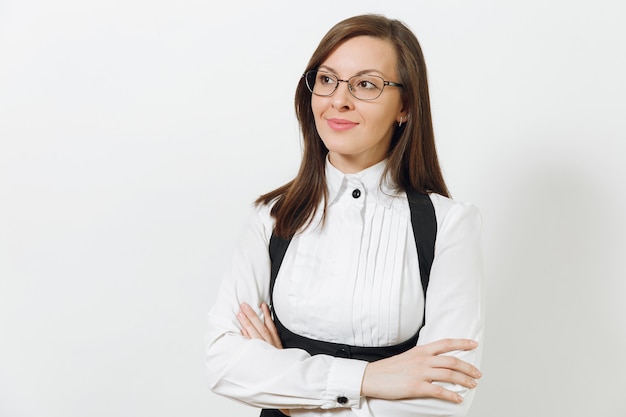 Mulher de negócios de cabelos castanhos bonita caucasiana jovem sorridente de terno preto, camisa branca e óculos de mãos cruzadas, isolado no fundo branco. Gerente ou trabalhador. Copie o espaço para anúncio.