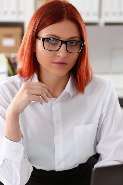 Mulher de negócios de cabelos vermelhos sentada no retrato do escritório no local de trabalho