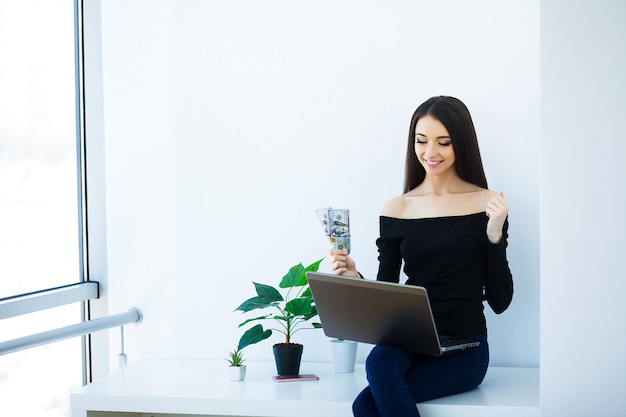 Mulher de negócios de escritório sorrindo e sentado em cima da mesa.