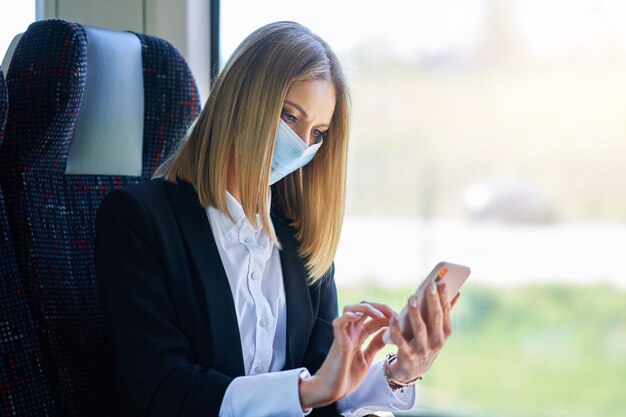 Mulher de negócios de metrô mascarada em transporte público usando smartphone