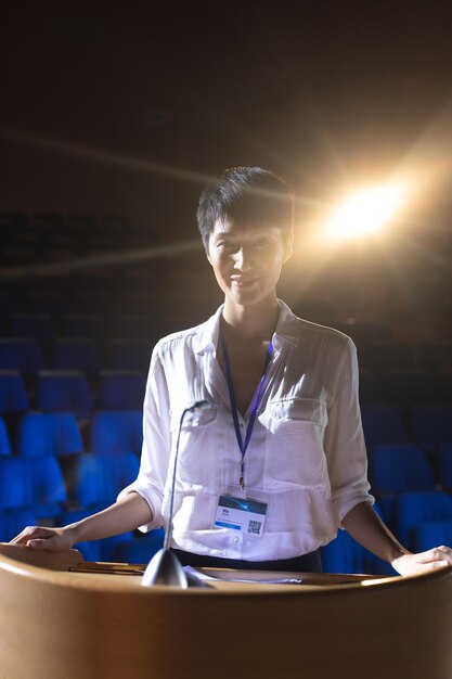 Foto mulher de negócios de pé no pódio no palco no auditório