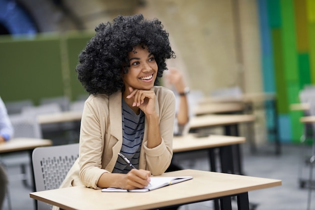 Mulher de negócios de raça mista feliz sentada à mesa no moderno espaço de coworking ouvindo o treinador