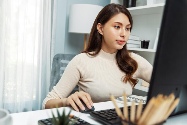 Mulher de negócios de roupa casual procurando relatório no computador e escrevendo postulado