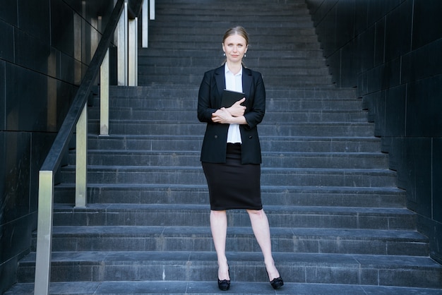 Mulher de negócios de terno com um diário parada na escada