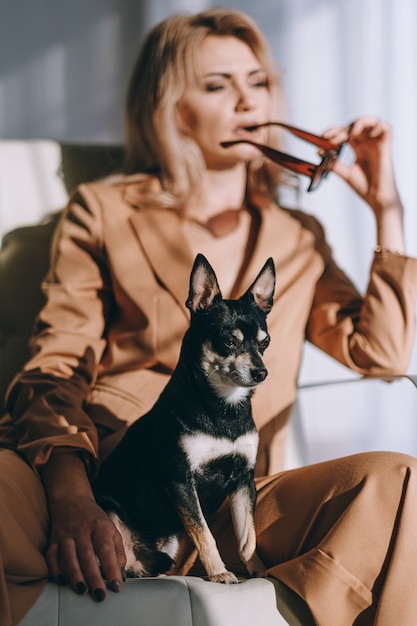 Mulher de negócios de terno sentada em uma cadeira nos braços com um cachorrinho