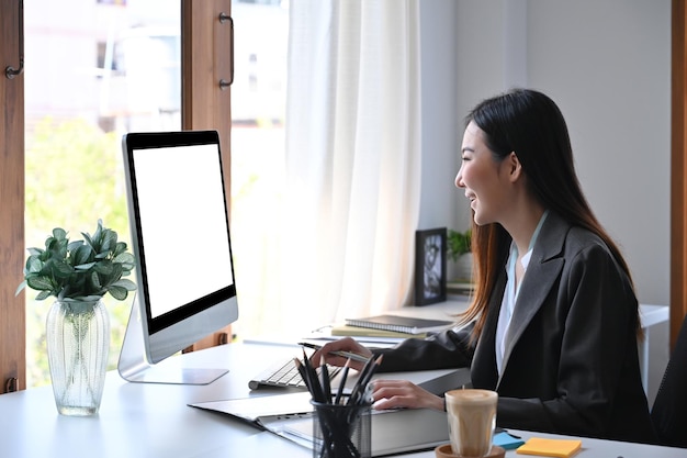 Mulher de negócios de vista lateral verificando dados financeiros no computador.