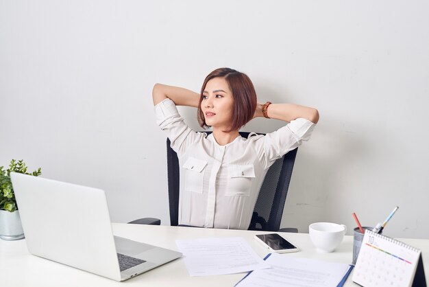 Mulher de negócios descansando no escritório após um dia de trabalho, com as mãos atrás da cabeça