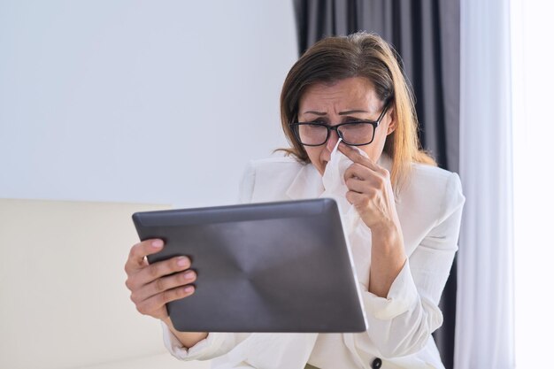 Mulher de negócios doente espirros no lenço fazendo videochamada, mulher olhando para a webcam do tablet digital, falando com um médico. Mulher fazendo uma videoconferência importante em casa