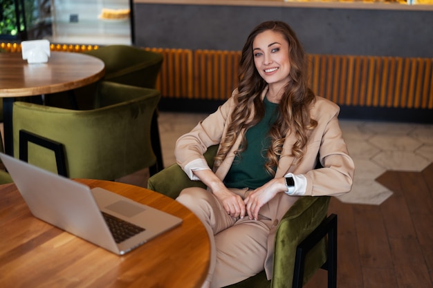 Mulher de negócios dona de restaurante usa laptop vestido elegante macacão sentado na mesa no restaurante com superfície do balcão de bar caucasiano feminino pessoa de negócios interna