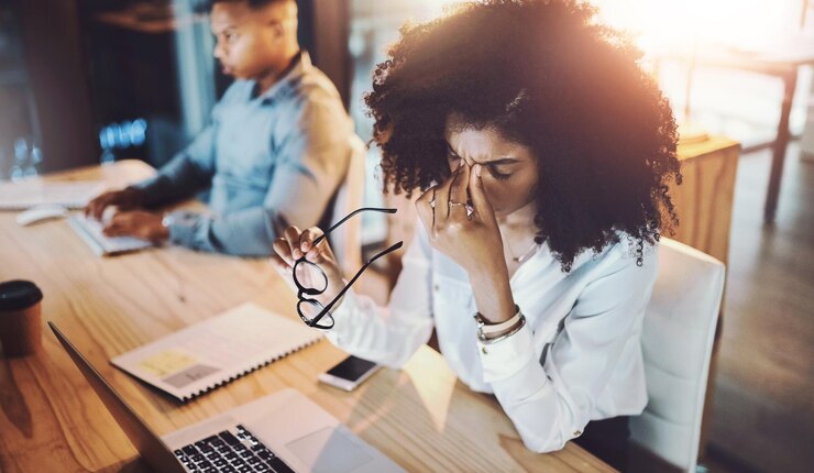 Foto mulher de negócios e dor de cabeça de estresse na mesa com esforço ocular sobrecarregado de trabalho e prazo de trabalho à noite empregados profissionais e fadiga no escritório de coworking com esgotamento internet glitch e dor