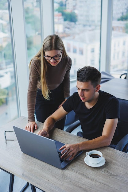 Mulher de negócios e empresário estão procurando algo no laptop o conceito de cooperação empresarial e trabalho em equipe jovens millennials sorridentes à mesa no escritório pessoas modernas de sucesso