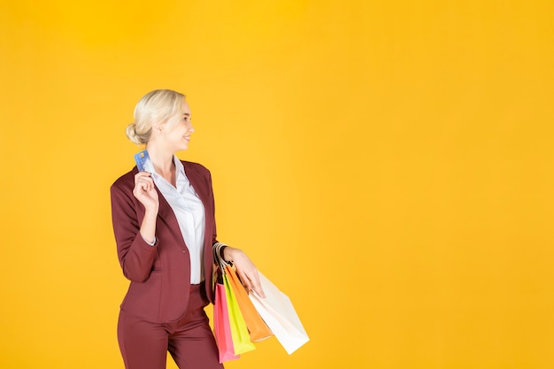 Mulher de negócios é feliz com as compras em fundo amarelo studio