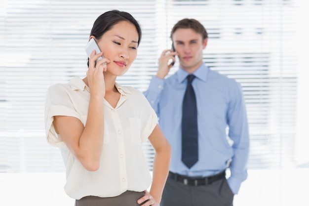 Mulher de negócios e homem usando celulares no escritório