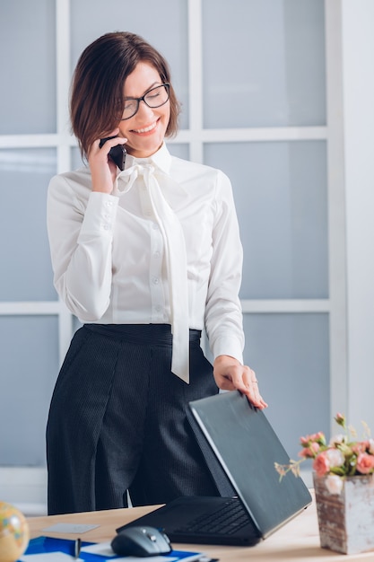 Mulher de negócios elegante falando ao telefone no escritório.