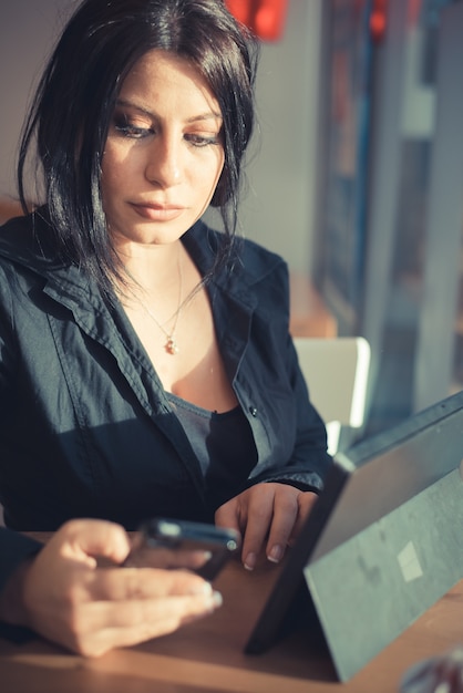 mulher de negócios elegante lindo cabelo preto longo usando tablet e smartphone