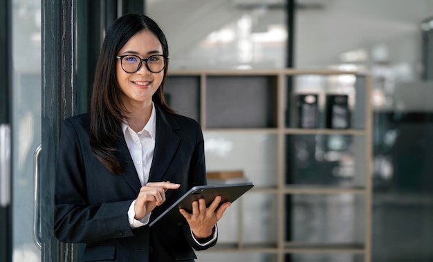 Mulher de negócios elegante no escritório com tablet digital sorrindo e olhando para a câmera