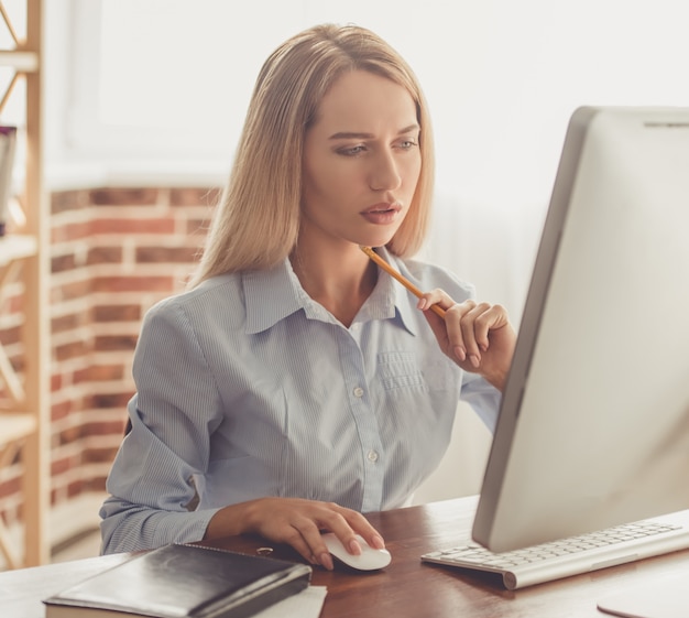 Mulher de negócios em camisa formal está usando um computador