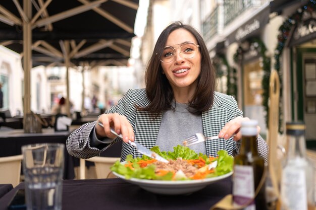 Mulher de negócios em óculos comendo salada na mesa do café