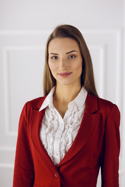 Mulher de negócios em pé vermelho no escritório moderno. Tiro na cabeça de uma jovem empresária.