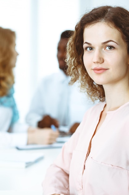 Mulher de negócios em reunião no escritório, de cor branca. Grupo de empresários multiétnicos.