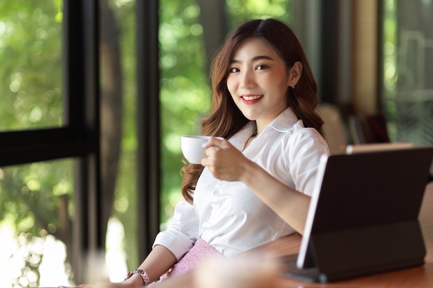 Mulher de negócios em roupa formal bebe café relaxado com um bom café e uma vista externa verde