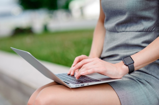 Mulher de negócios em um vestido elegante usando laptop na rua