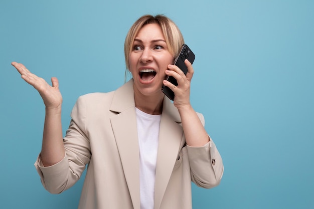 Mulher de negócios em uma jaqueta com cabelo loiro fala ao telefone com um banco em um fundo de estúdio