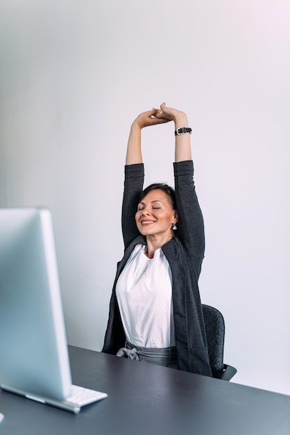 Foto mulher de negócios encantadora que estica as mãos na mesa de escritório.