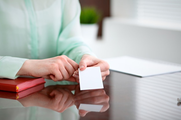 Mulher de negócios entrega uma blusa verde, sentado em uma mesa em um escritório e oferece cartão de visita.