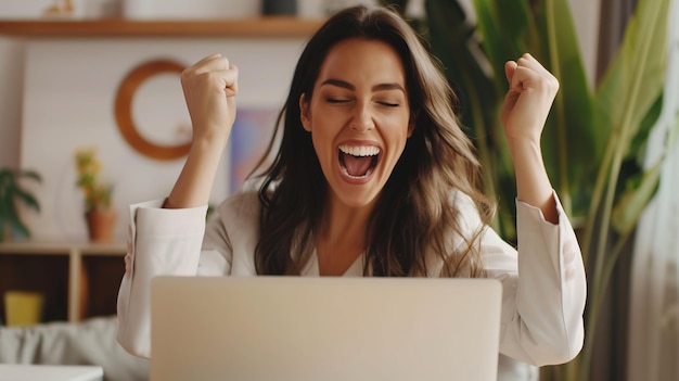 Mulher de negócios entusiasmada comemorando o sucesso na frente do laptop no escritório