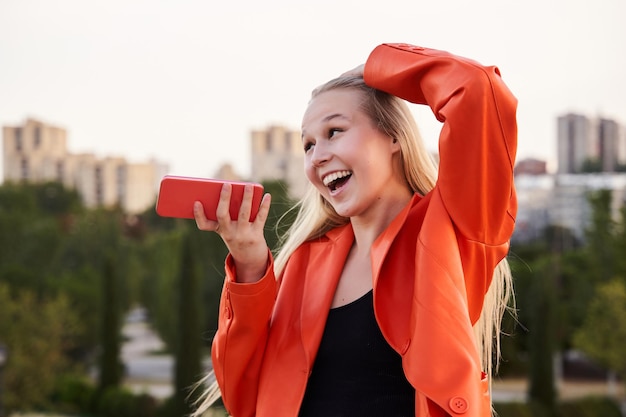 Mulher de negócios enviando áudio com a vida da cidade de telefone inteligente