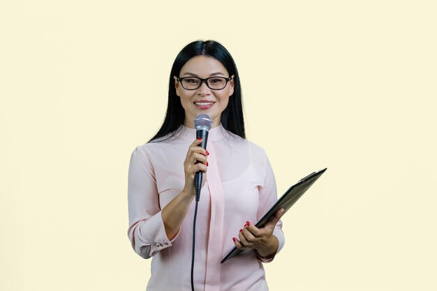 Mulher de negócios está dando um discurso no microfone isolado em amarelo pastel