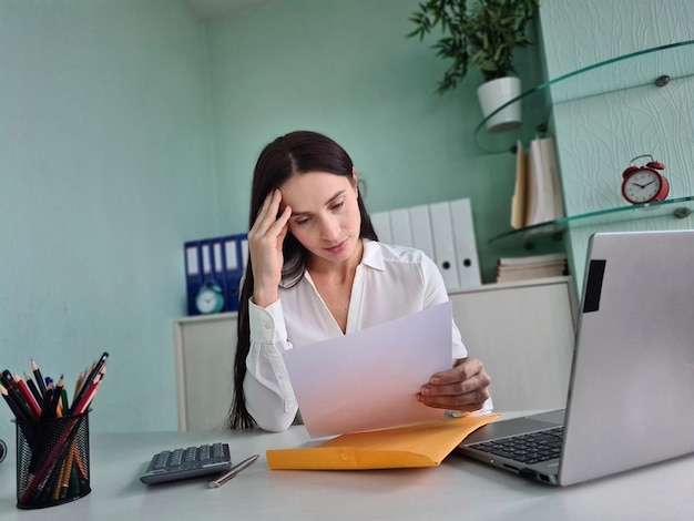 Mulher de negócios estressada em carta bancária com más notícias