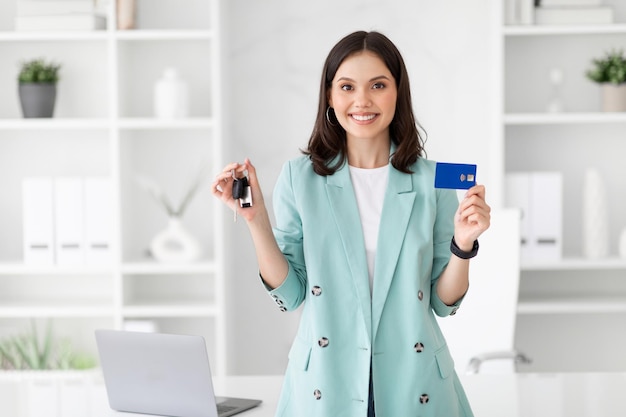 Mulher de negócios europeia do milénio Glad recomendando cartão de crédito e chaves de carro
