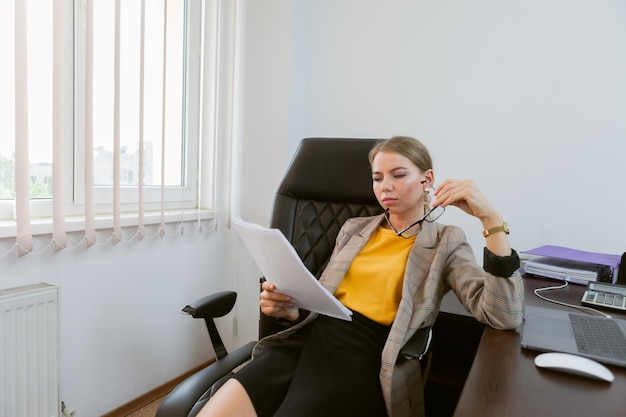 Mulher de negócios examina cuidadosamente documentos em seu escritório
