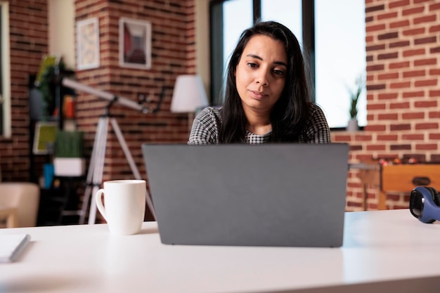 Mulher de negócios fazendo trabalho on-line remoto em casa, usando laptop para enviar e-mail e analisar informações de pesquisa. Trabalhando no relatório da internet com a rede de inicialização ou participando da aula da escola.