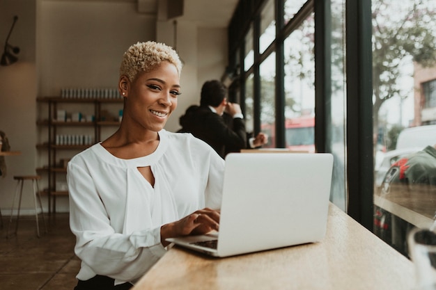 Mulher de negócios feliz em um café usando seu laptop