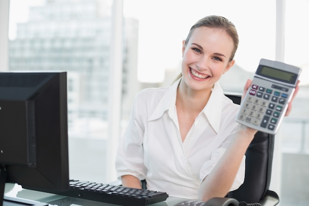 Foto mulher de negócios feliz mostrando calculadora sentada na mesa