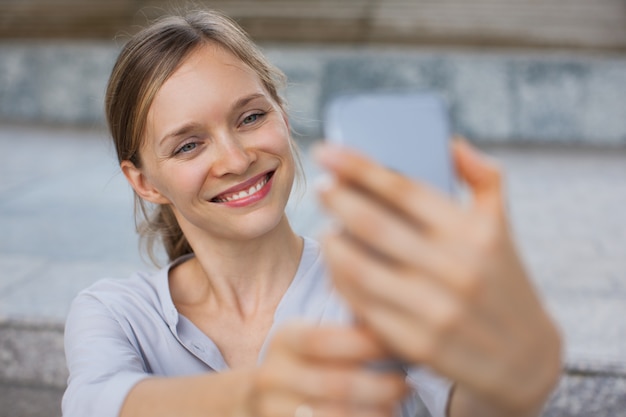 Mulher de negócios feliz tomando auto-retrato ao ar livre