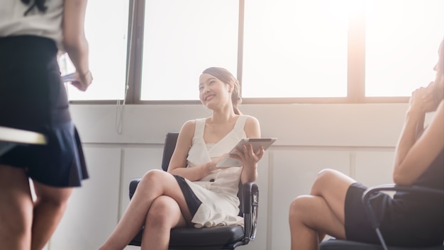 Mulher de negócios feliz trabalhando em um tablet e discutindo o trabalho positivo, conversando com o colega